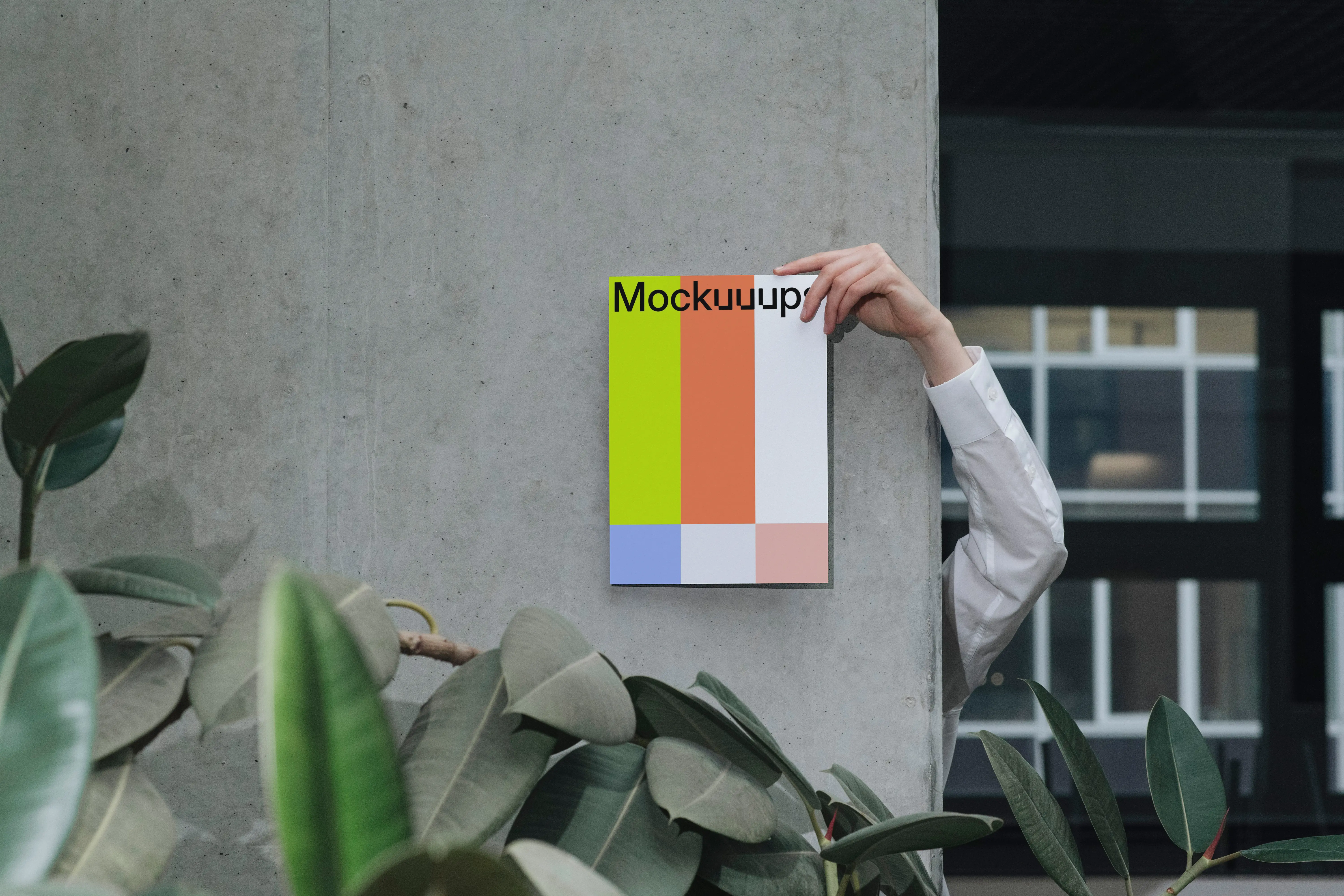 A4 mockup held against a concrete wall with indoor plants