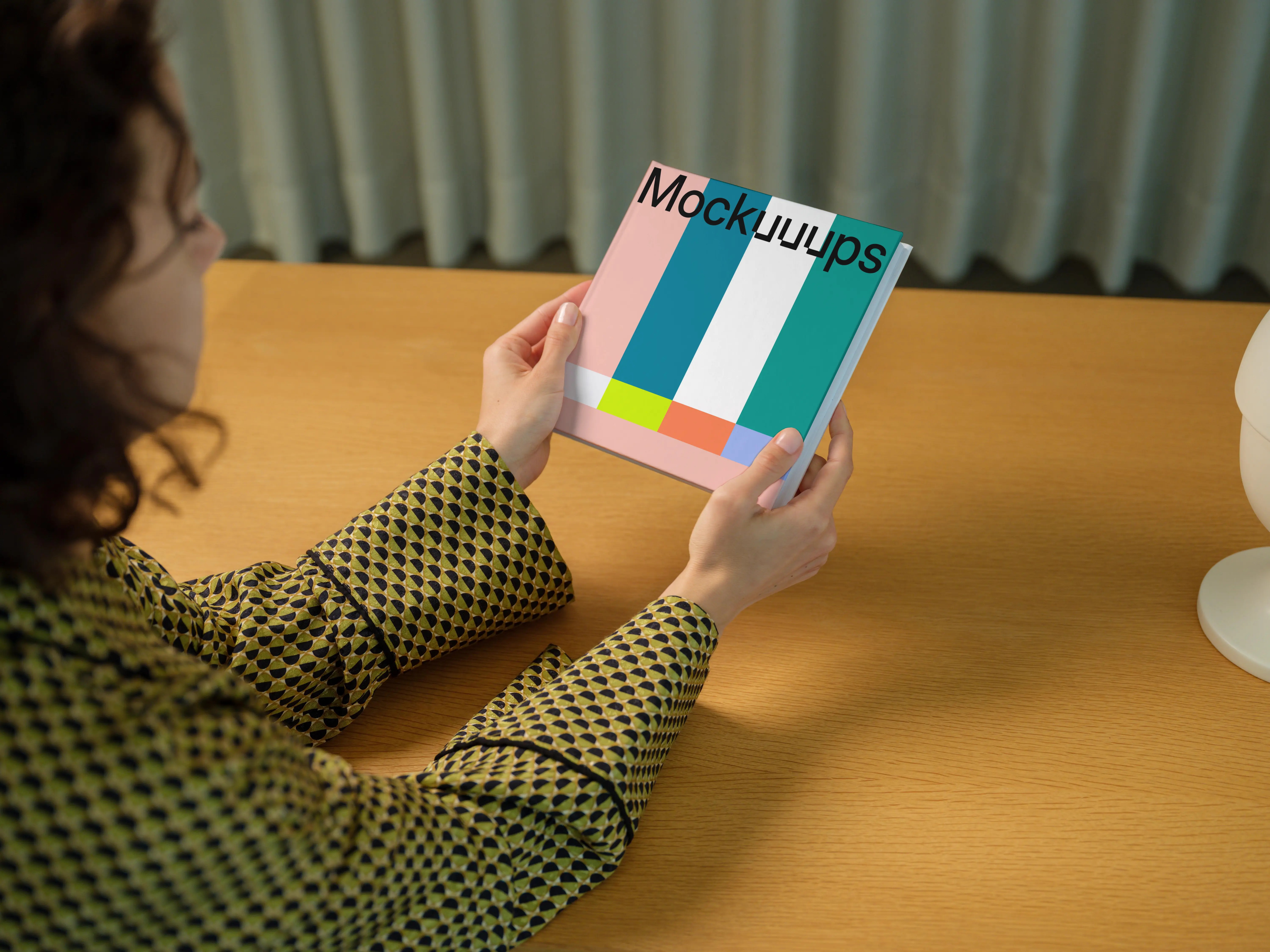 Book mockup held by a person at a wooden desk