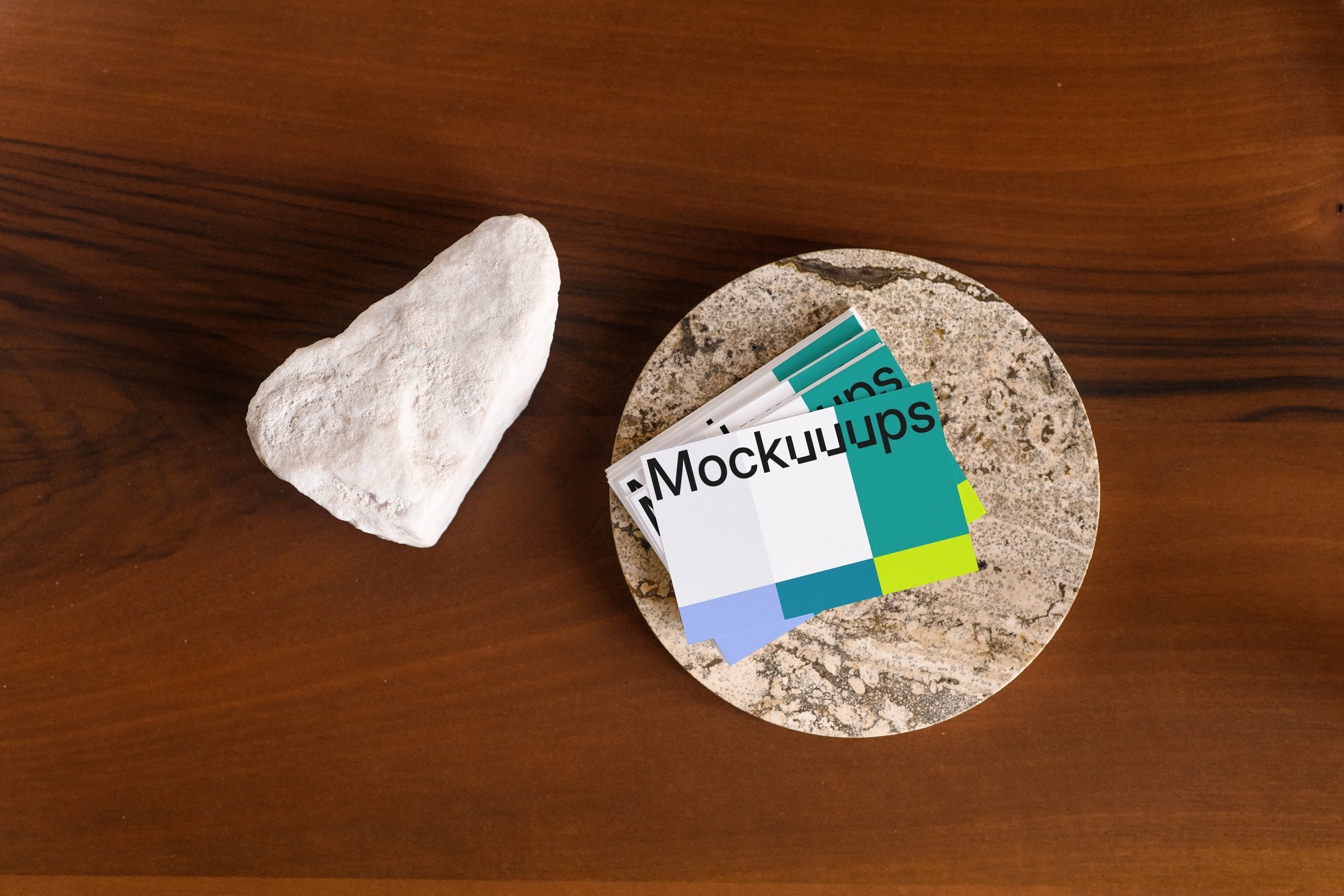 Business card mockup on a stone coaster with a wooden table