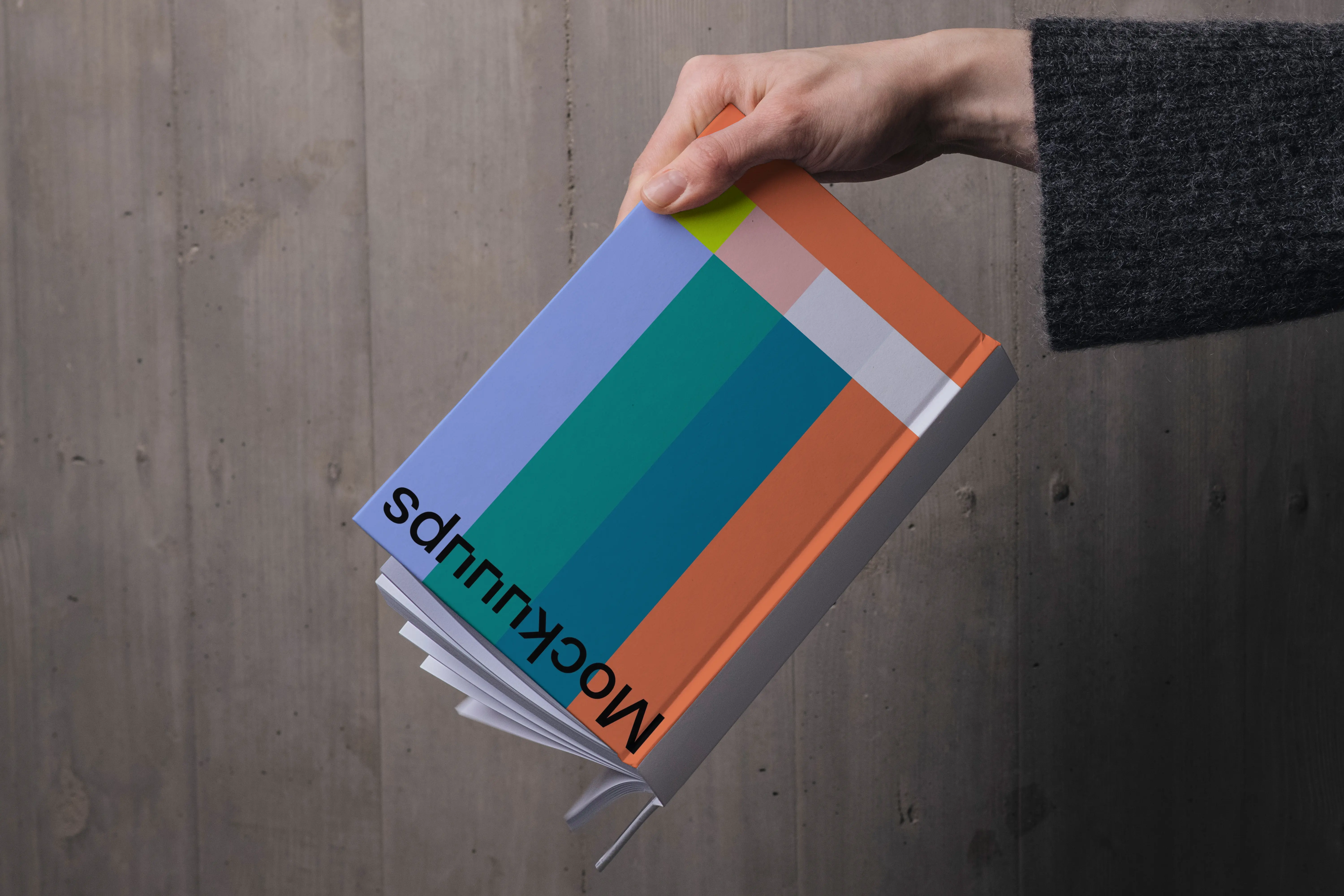 C-format book mockup held against wooden wall