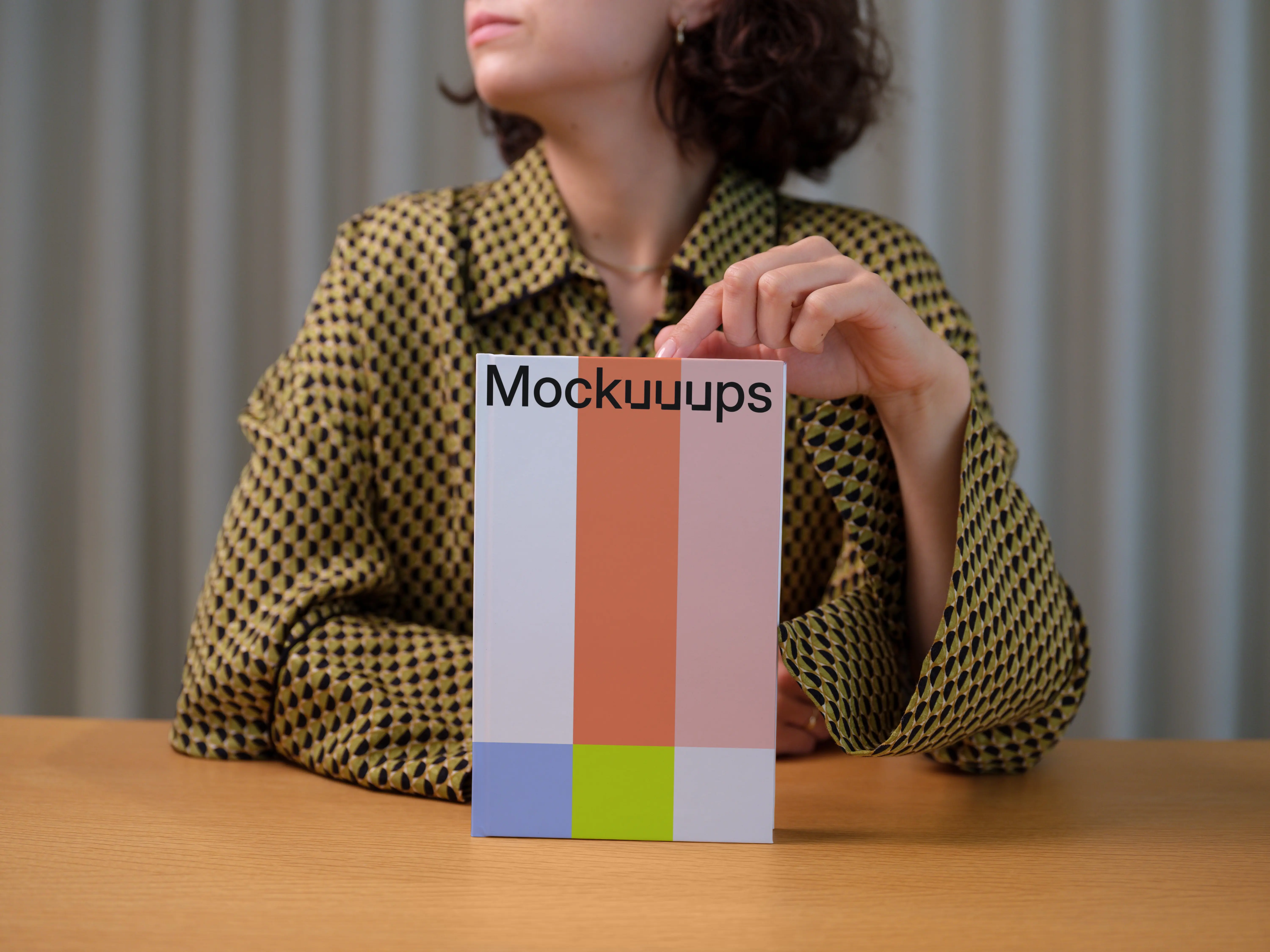 C-format book mockup held by person on wooden table