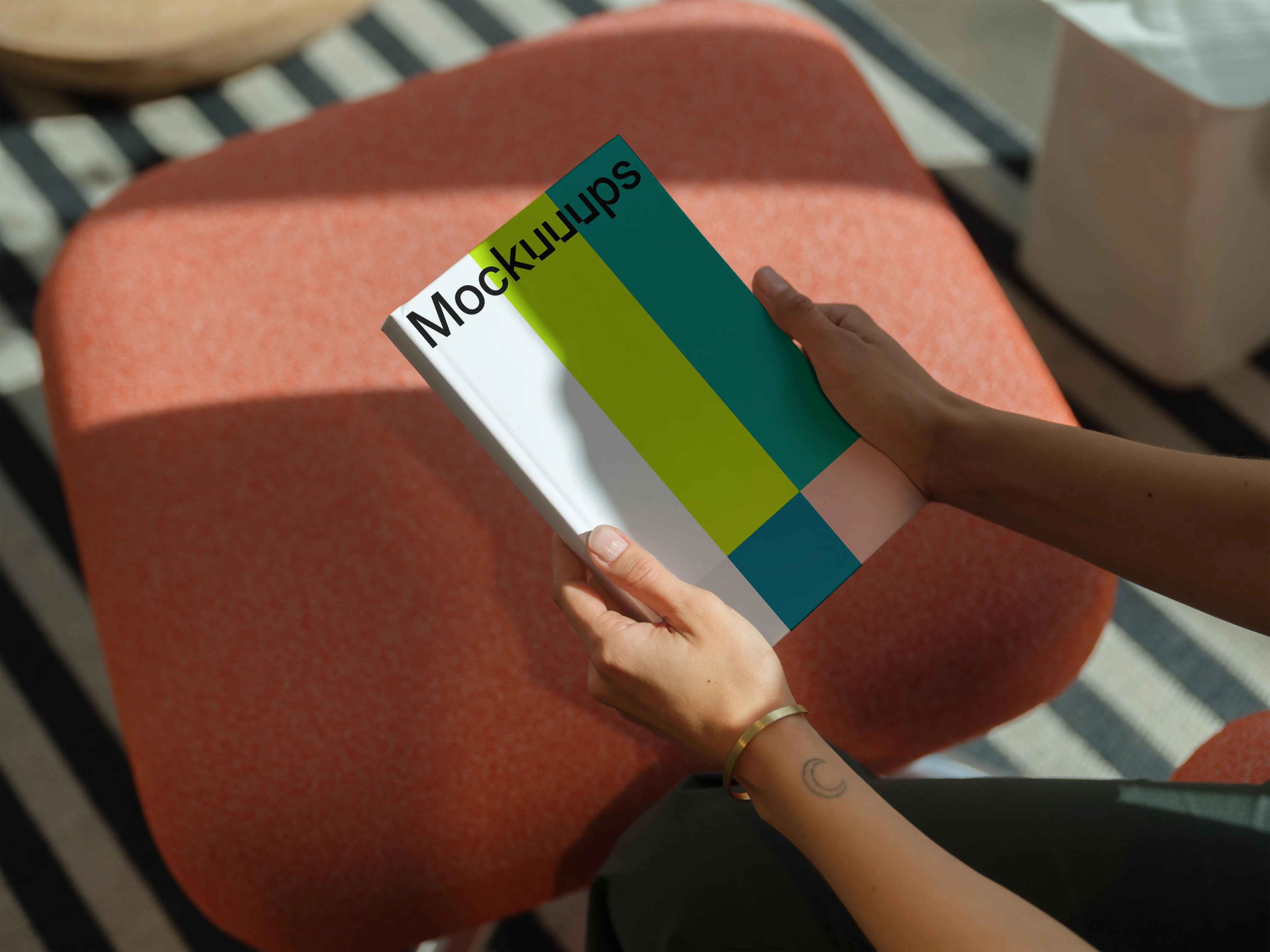 C-format book mockup in hands on a modern stool
