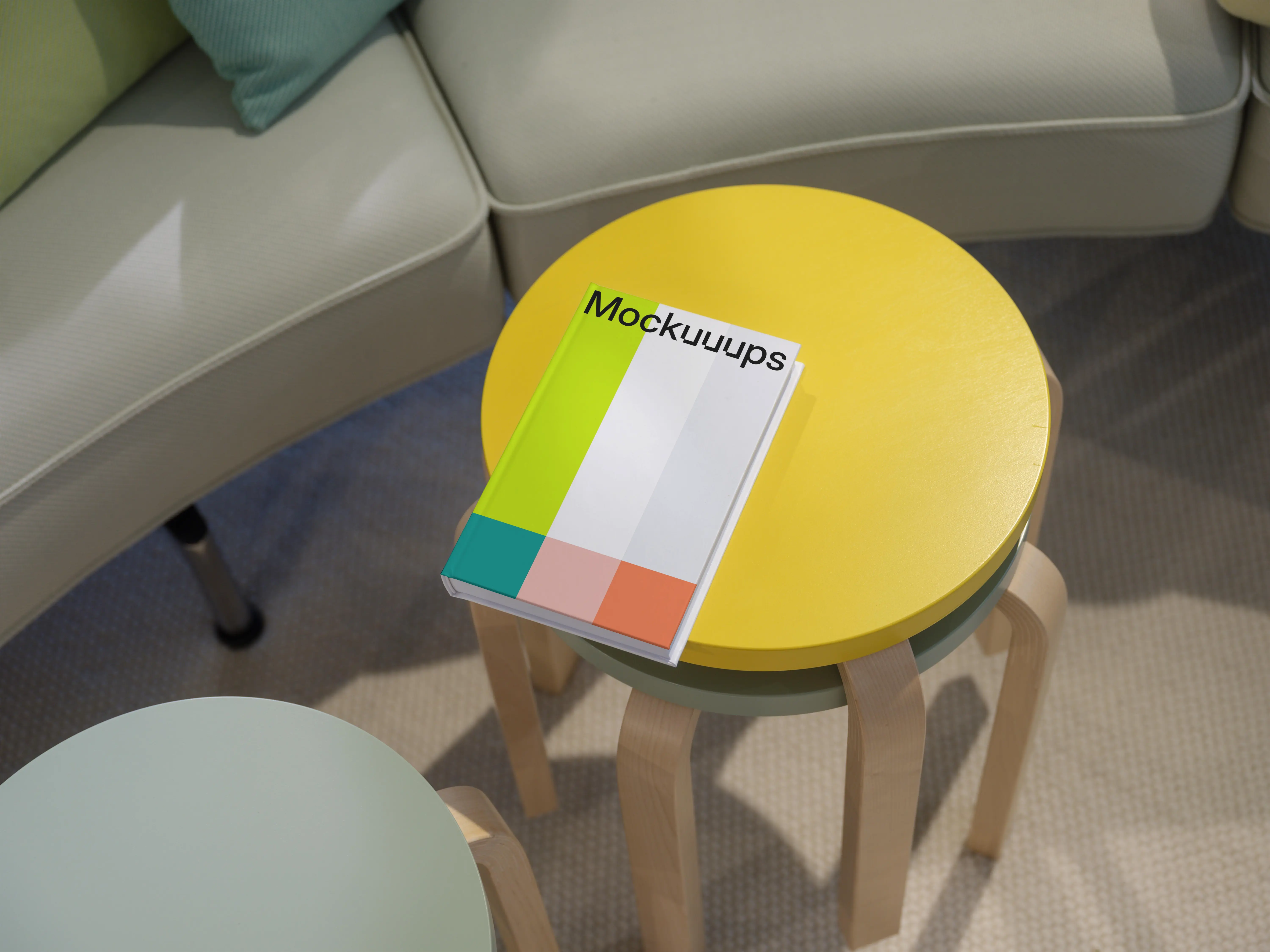C-format book mockup on colorful round tables in a cozy living area