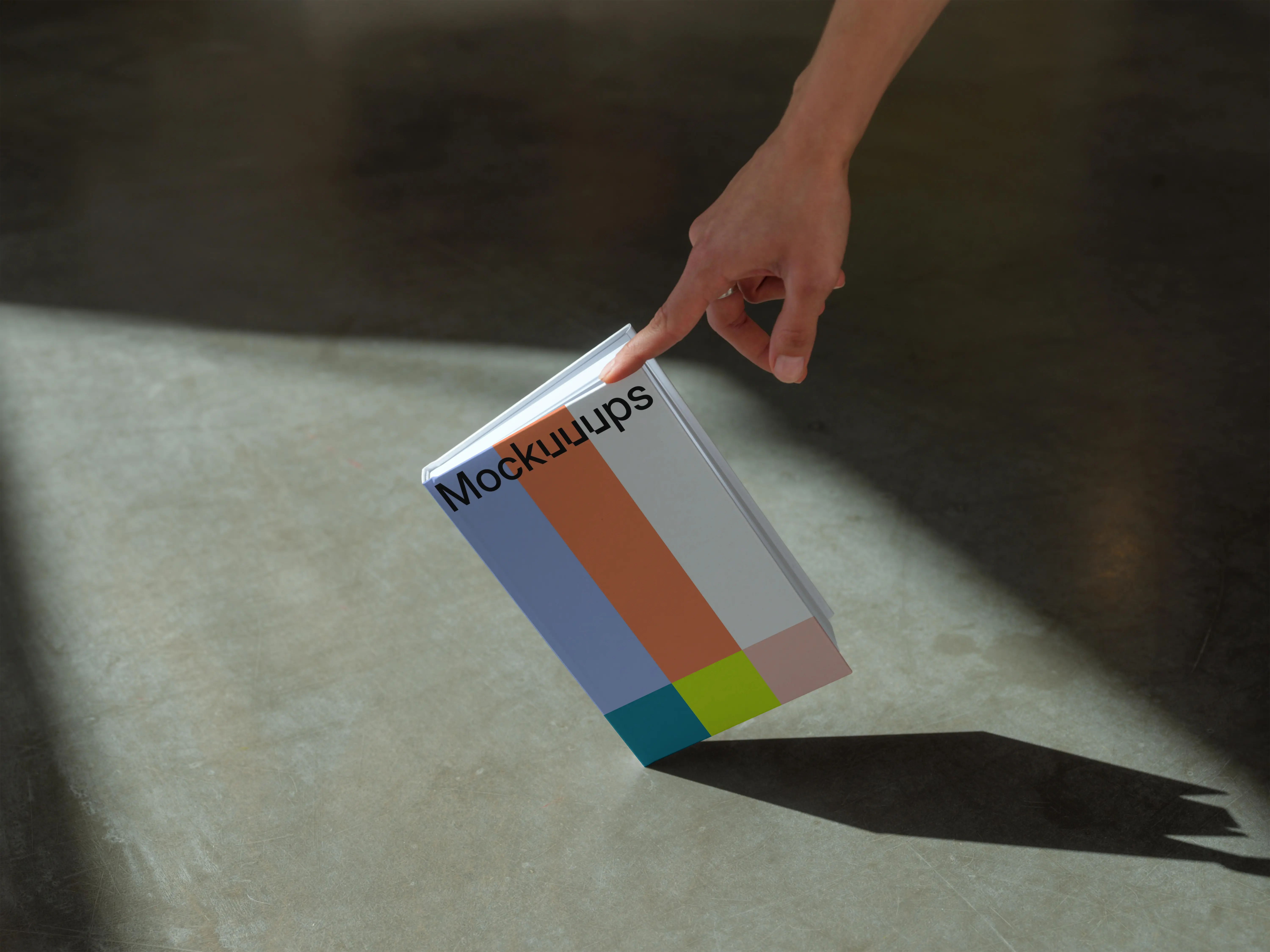 C-format book mockup with hand on concrete floor
