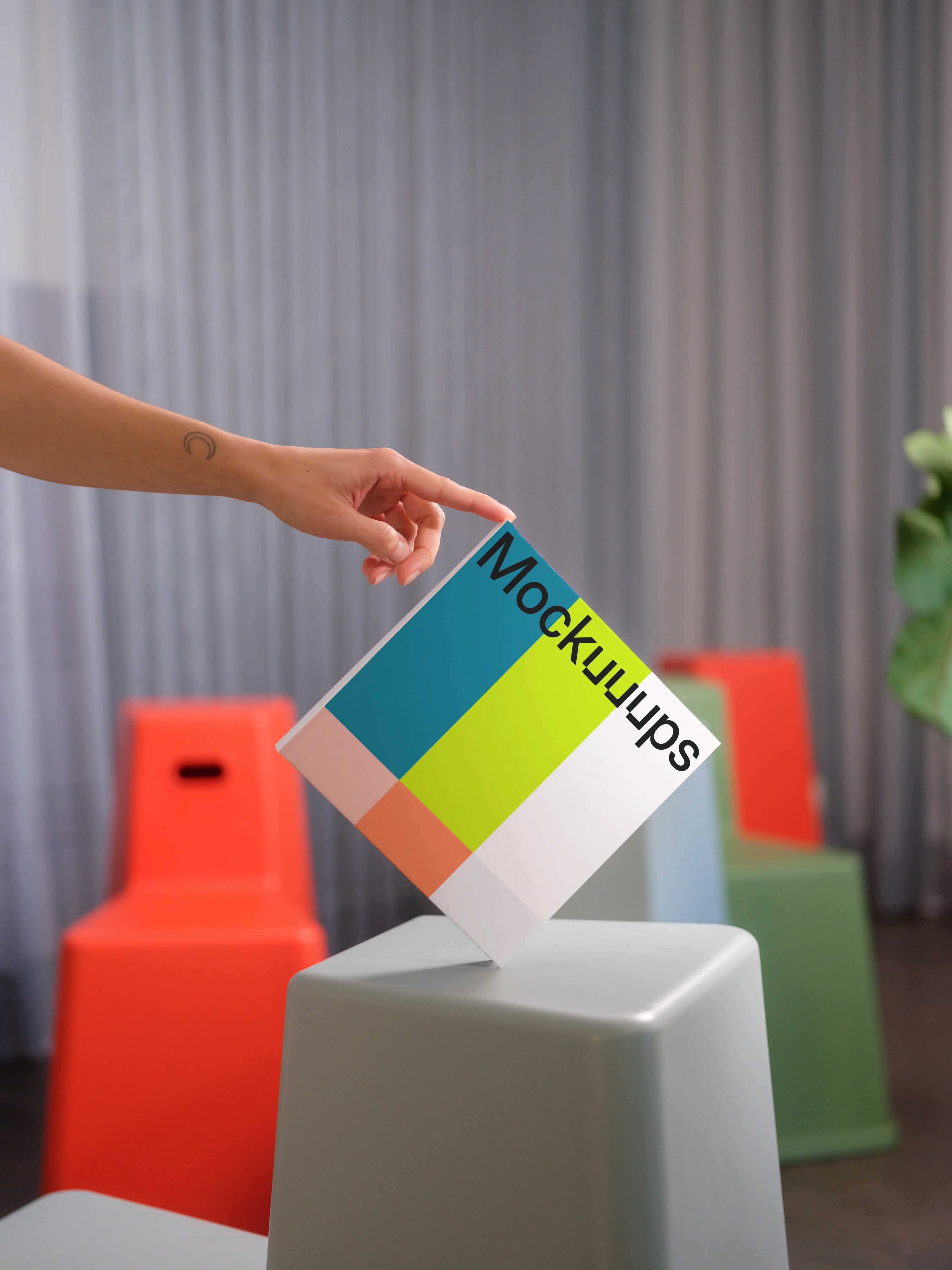 Hand-held square book mockup with modern seating