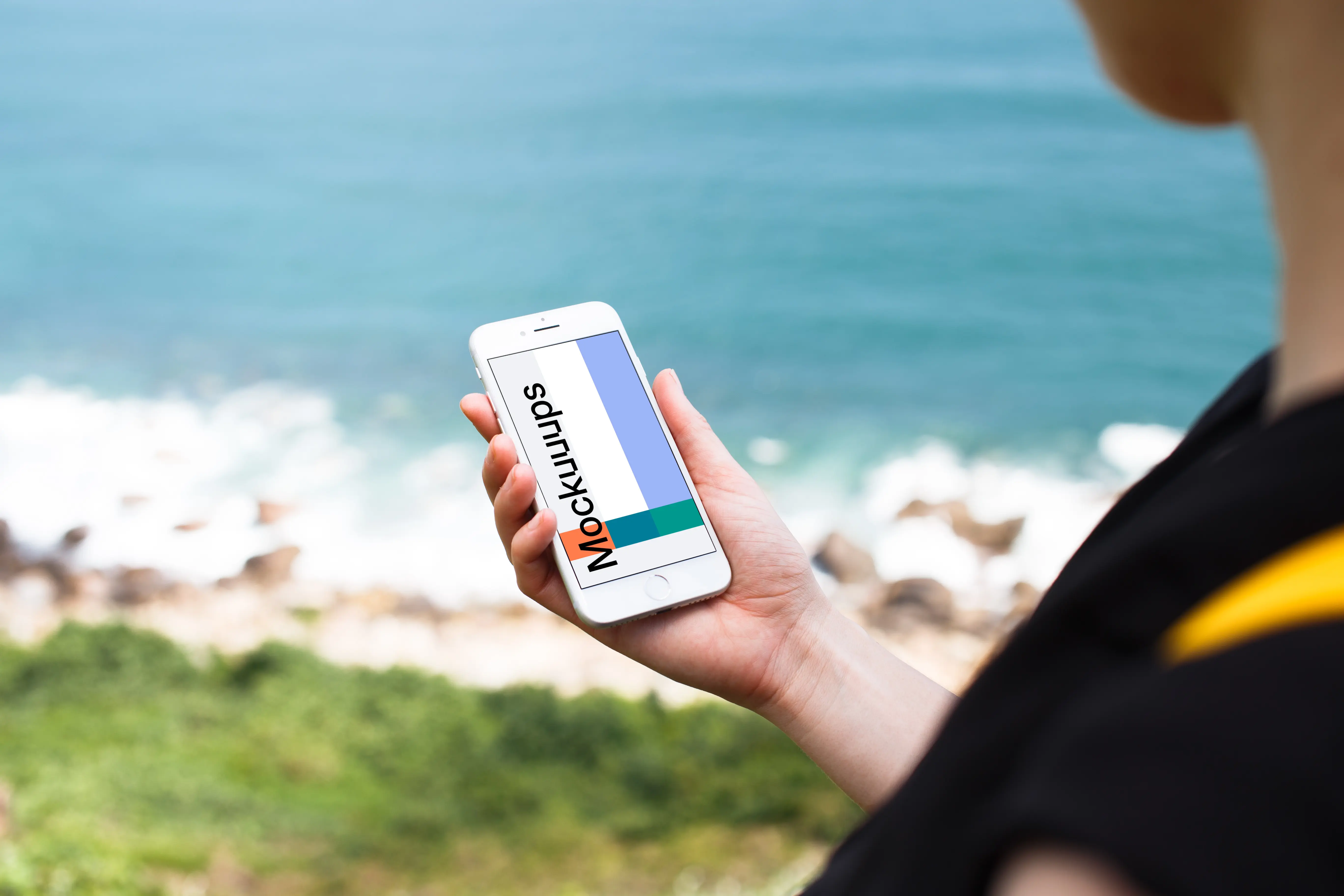 Holding iPhone 7 mockup next to the ocean