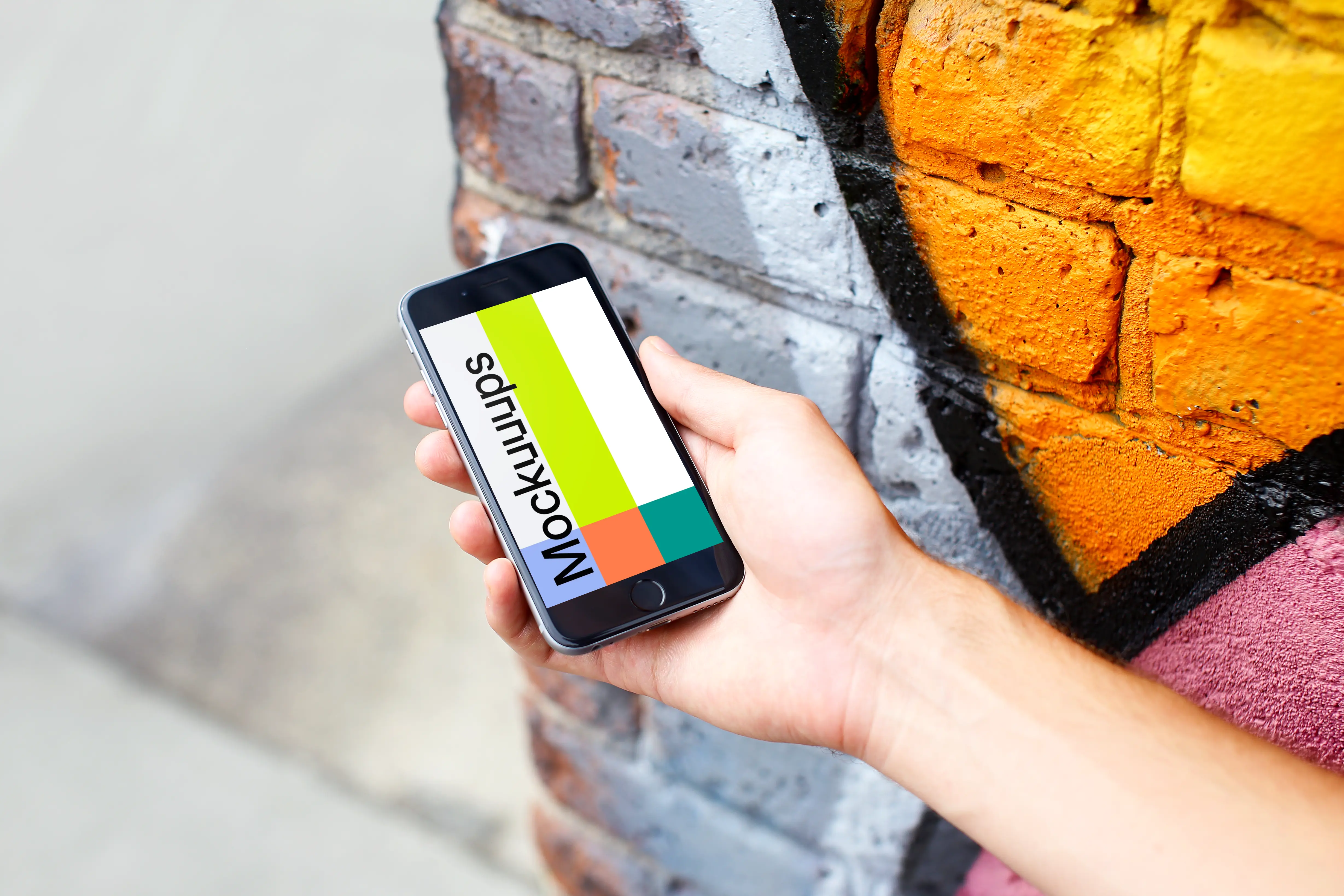 iPhone 6s Space Gray mockup next to the graffiti wall