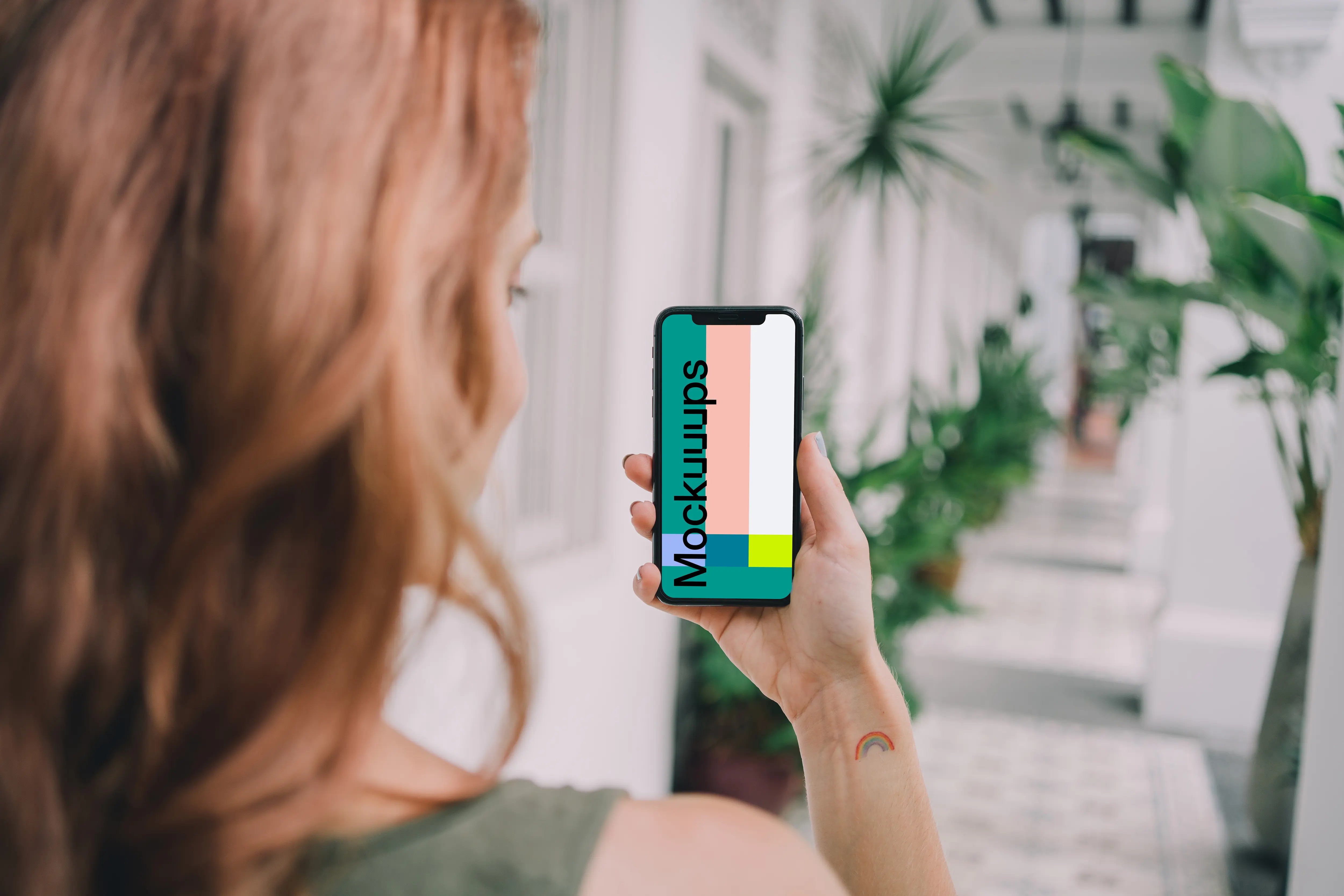 iPhone mockup held by user in a plant-filled corridor