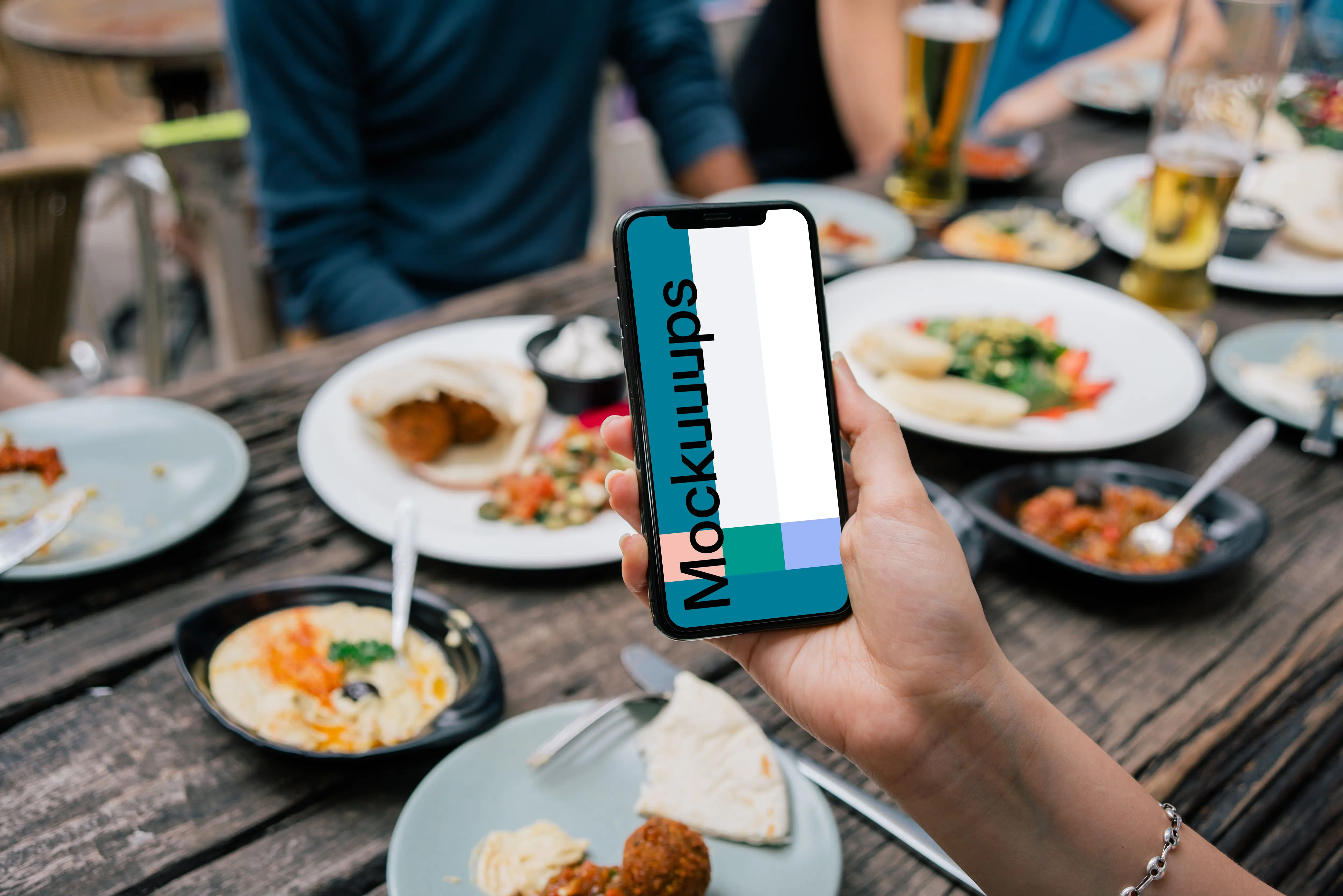 iPhone mockup in a user’s hand at dinner table