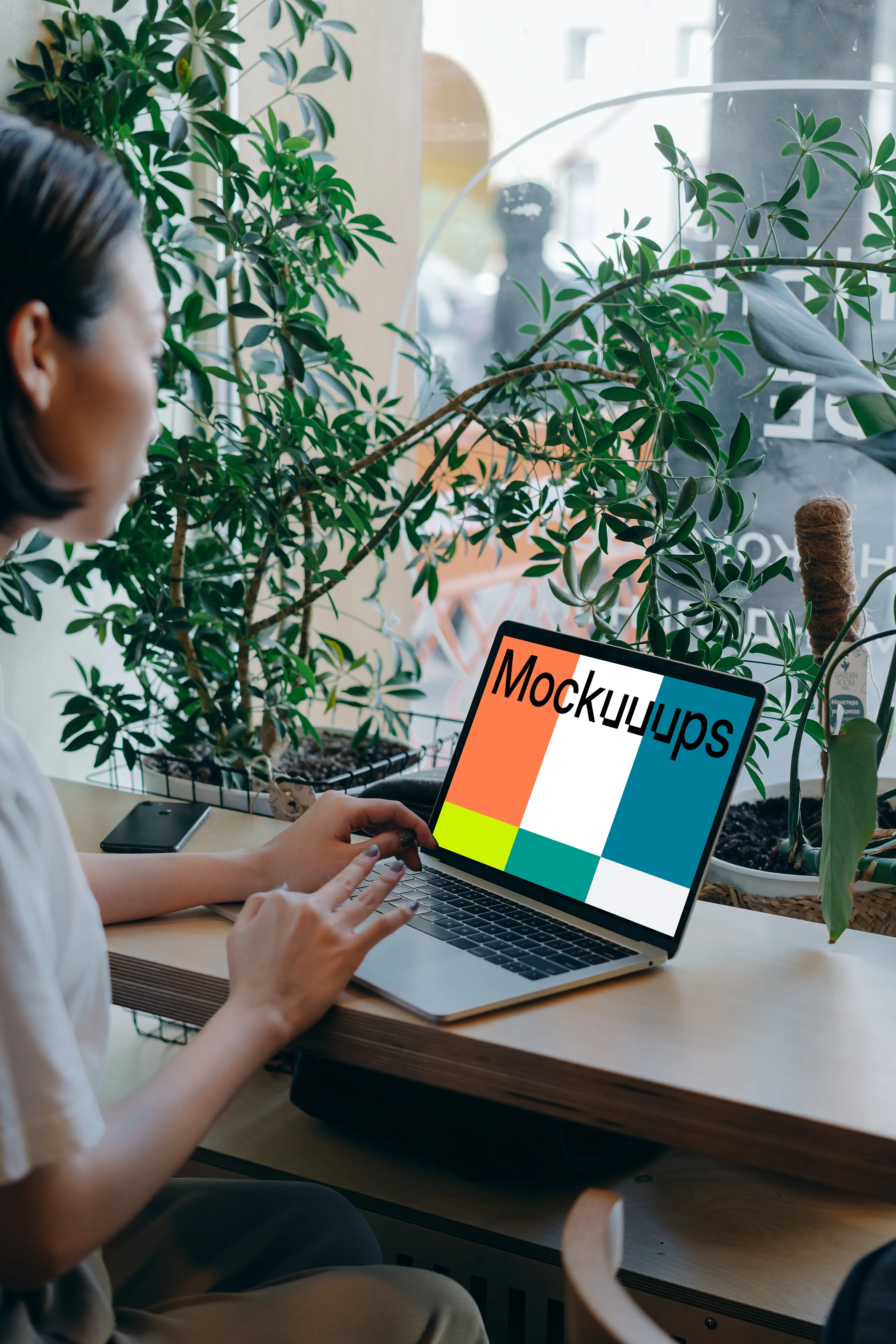 MacBook Air mockup in use by a lady with a lot of plants in the background