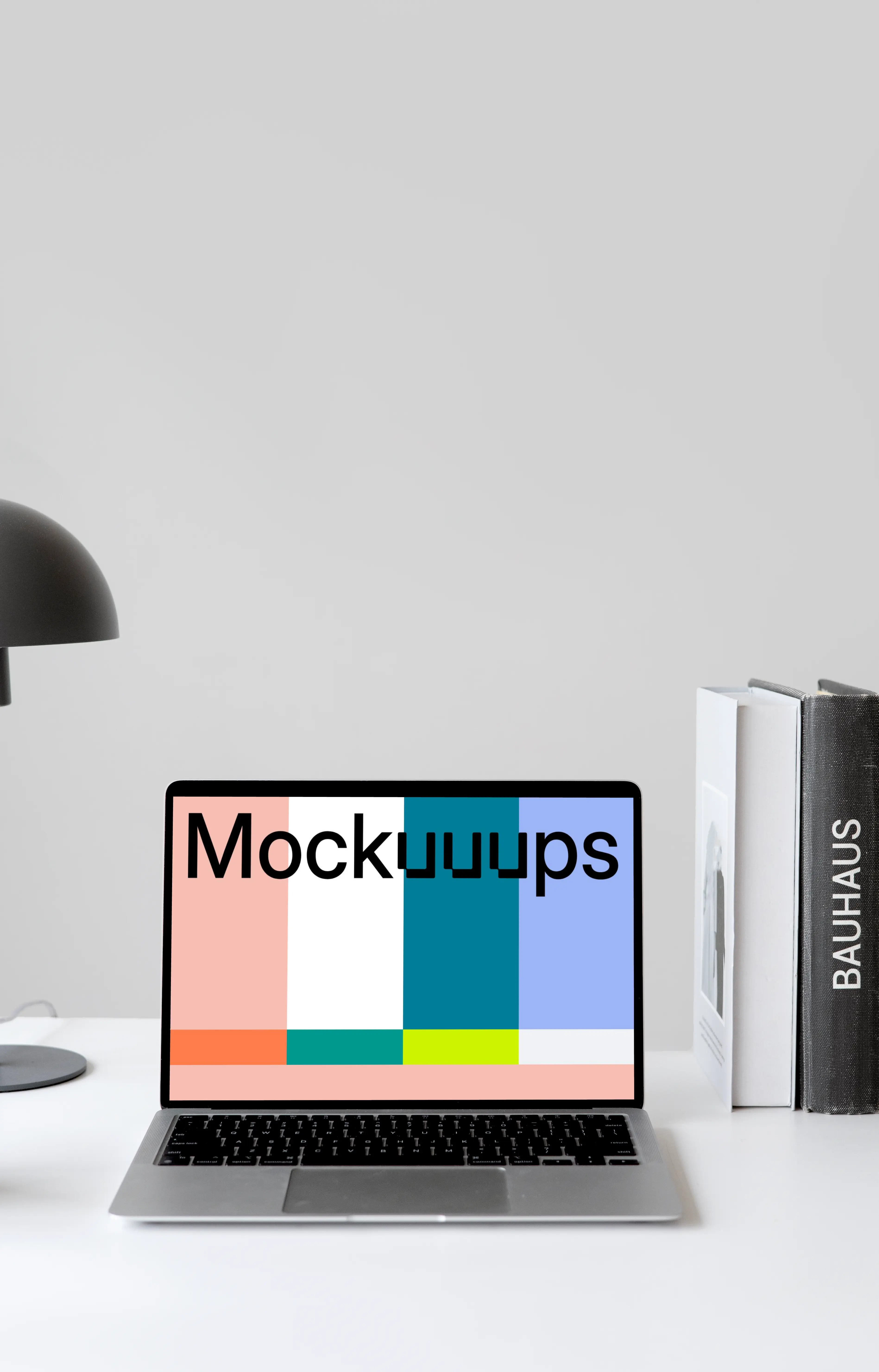 MacBook mockup on a white table with books stacked vertically at the side