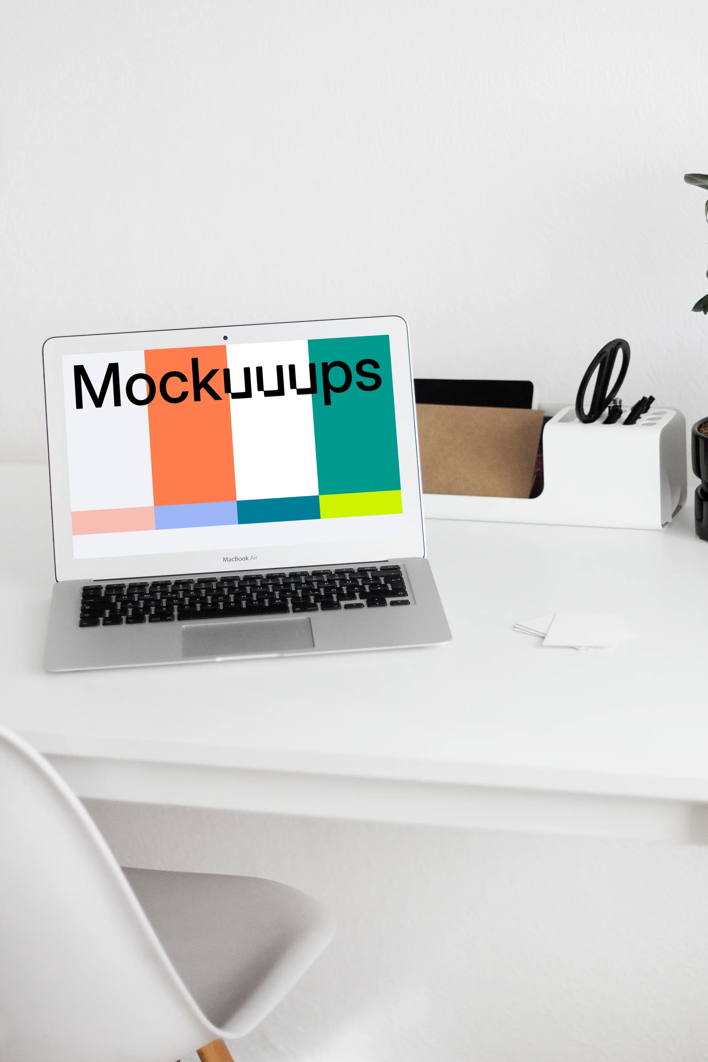 MacBook mockup on a white table with writing materials on the side