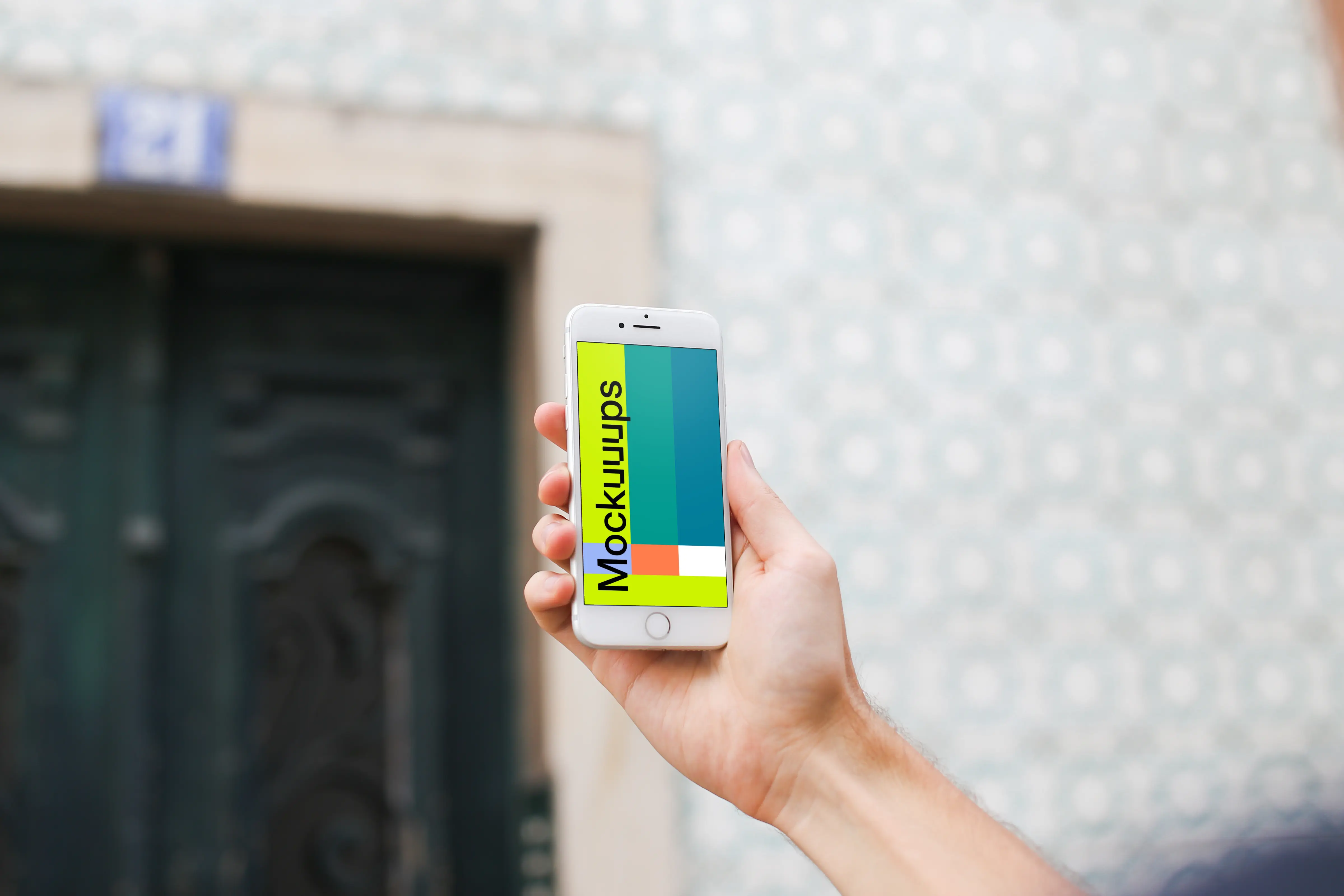 Man holding iPhone 7 mockup in front of the wall