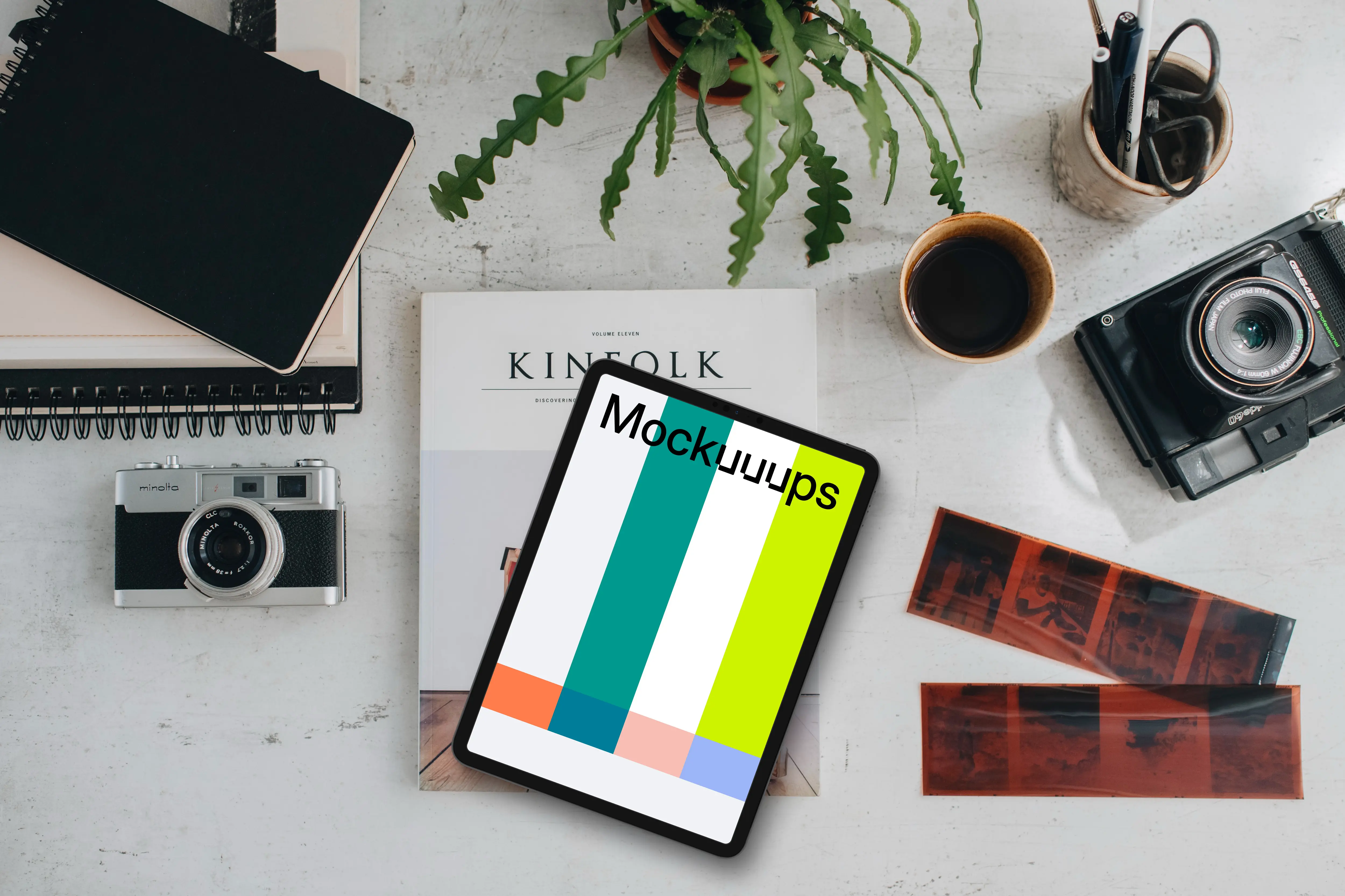 Top view of tablet mockup surrounded by analog cameras and negatives