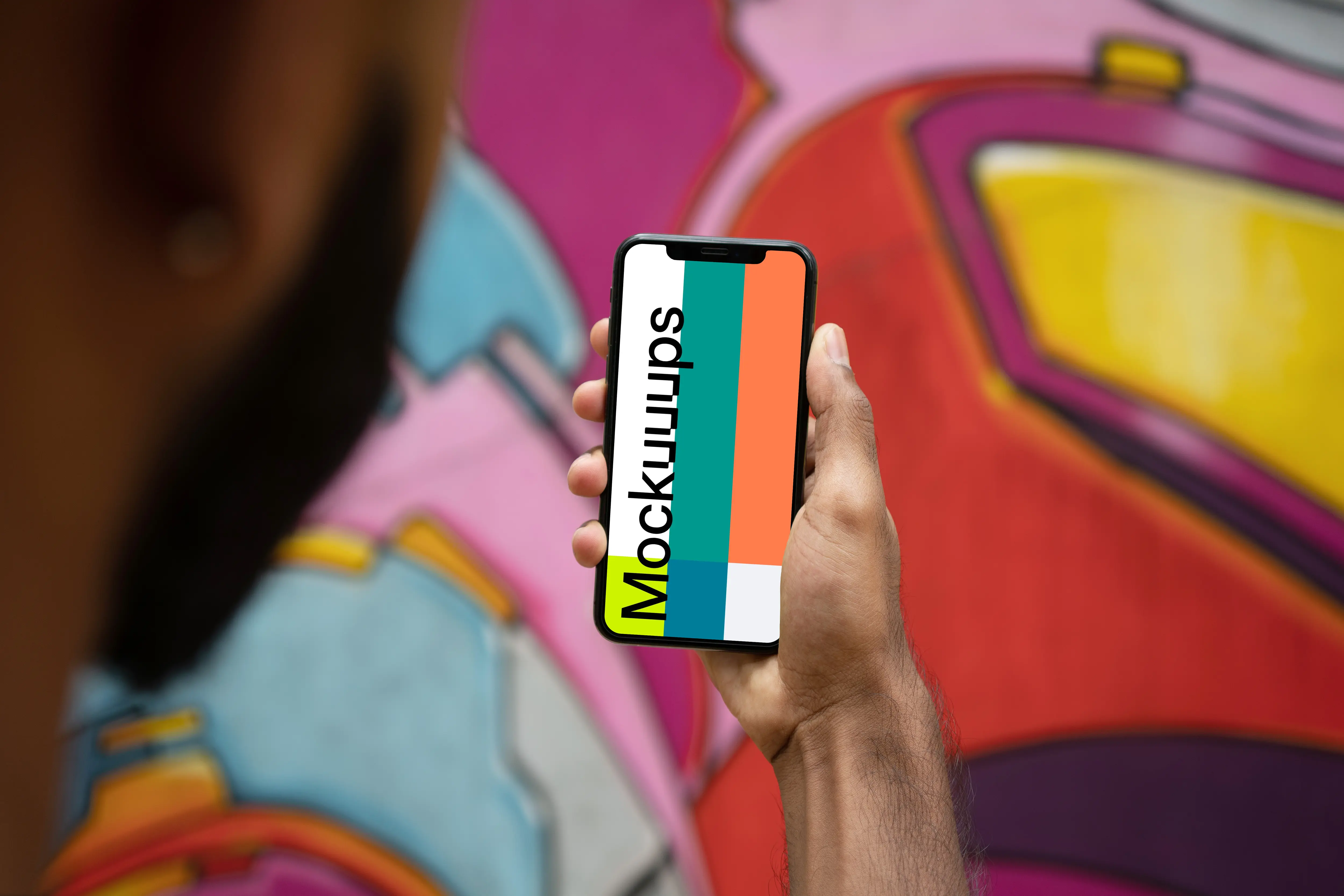 User holding iPhone in front of graffiti mockup
