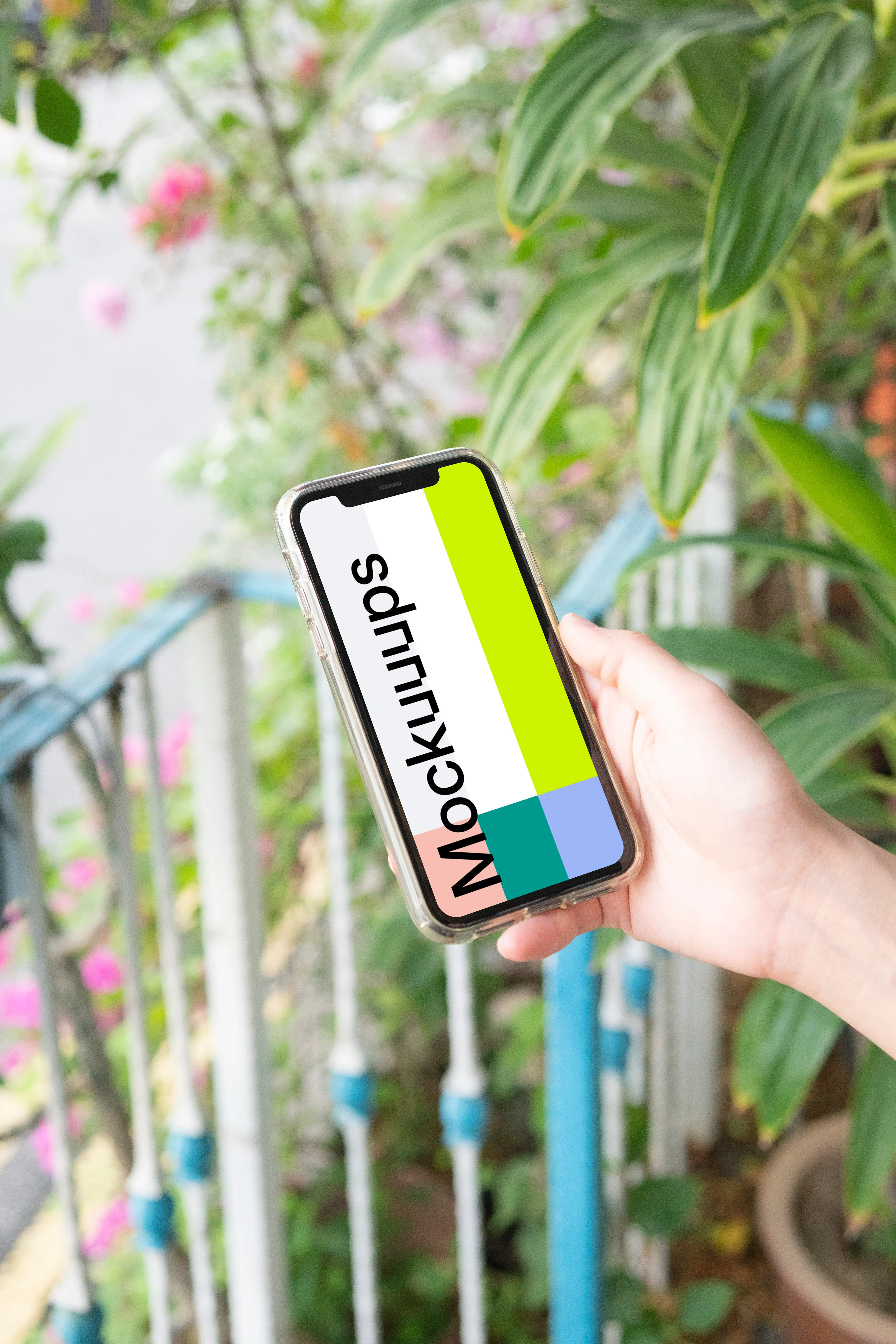 User holding up iPhone in a garden mockup
