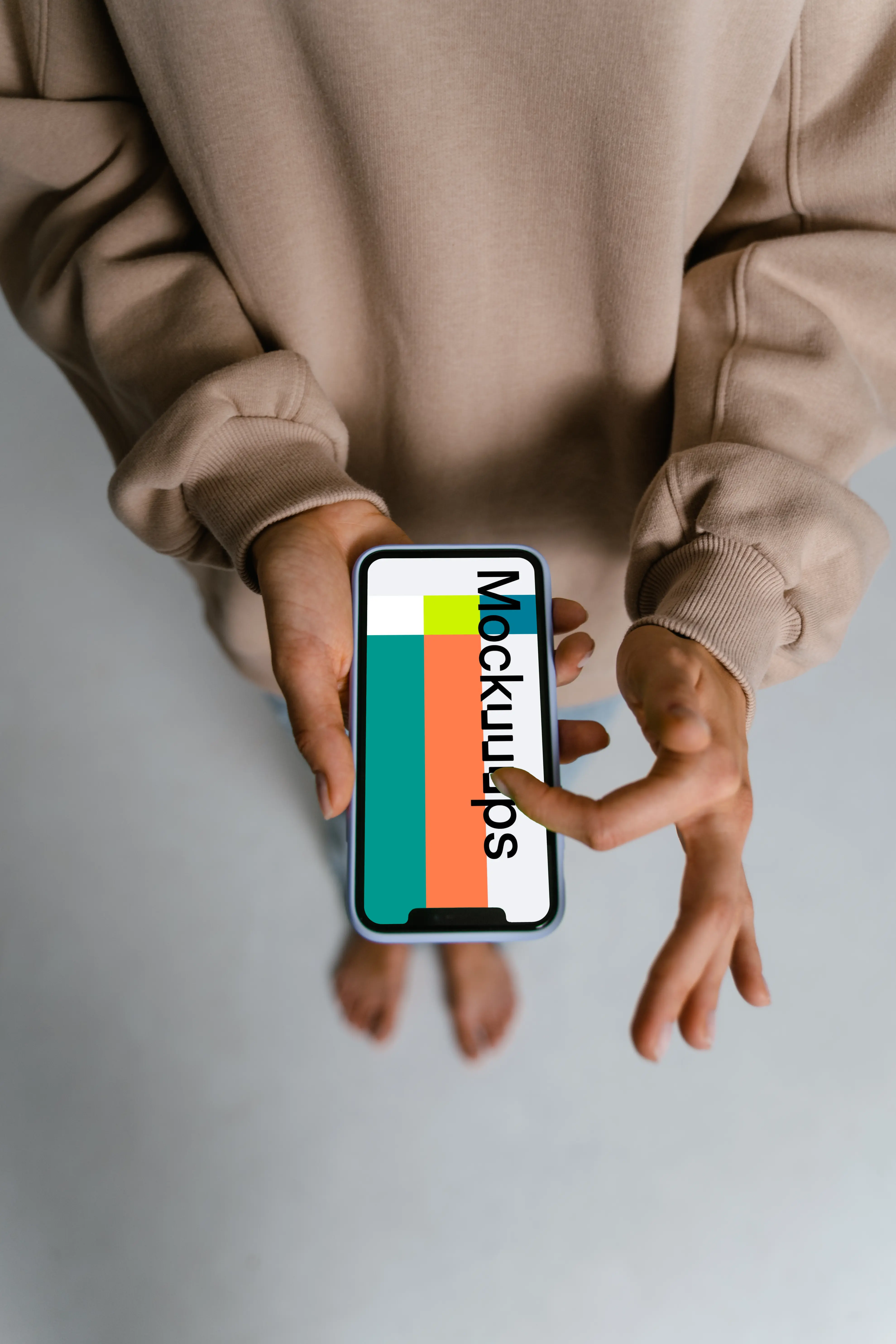 User in brown sweater scrolling through iPhone mockup
