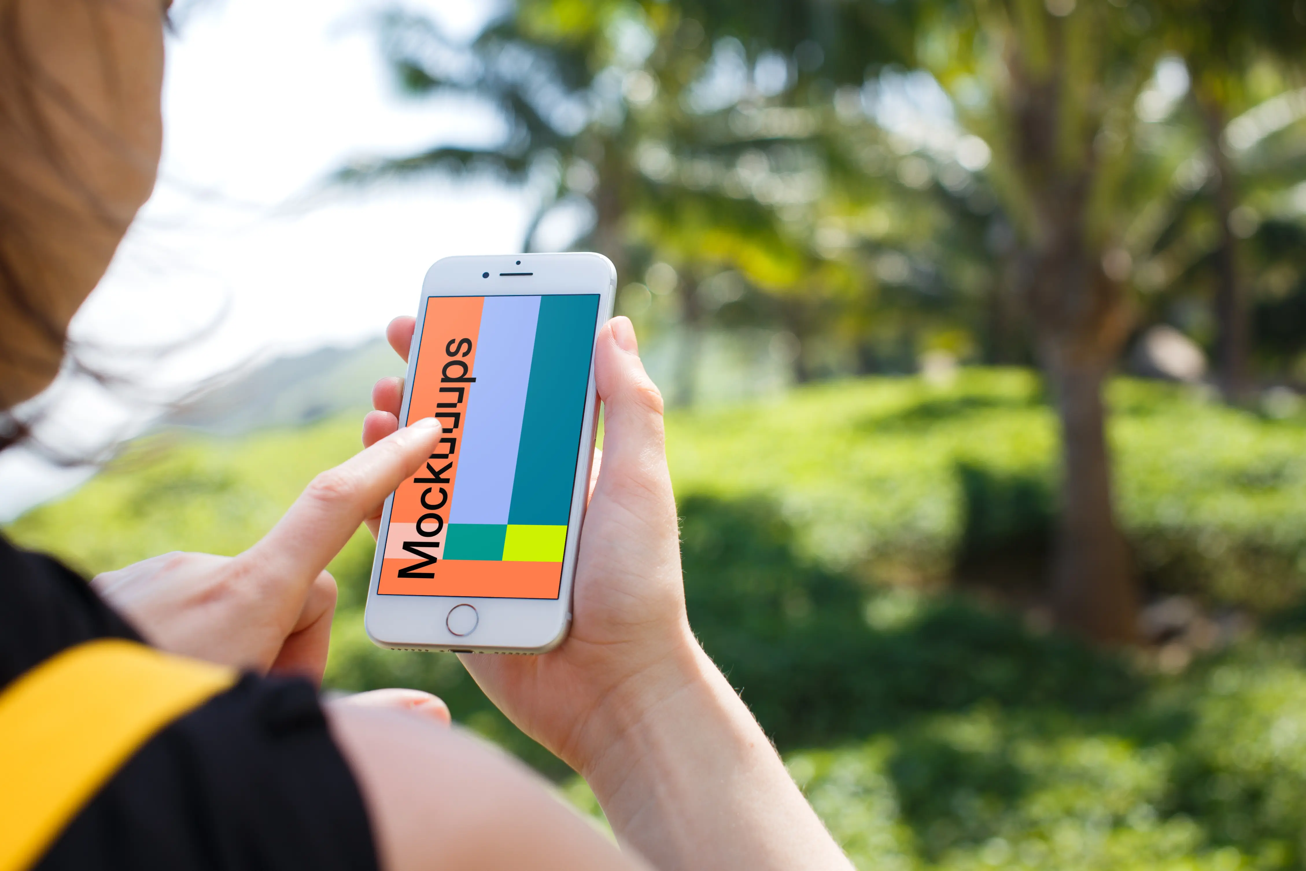 Woman holding iPhone 7 mockup in front of the palm tree