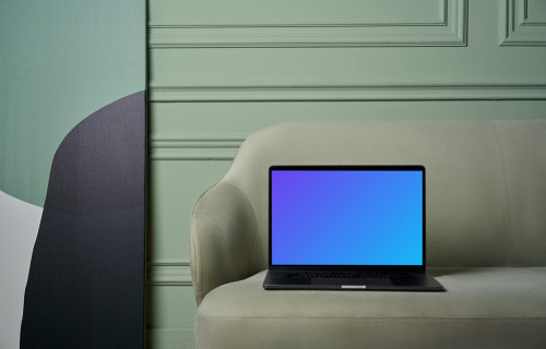 MacBook mockup on a couch with beside painting