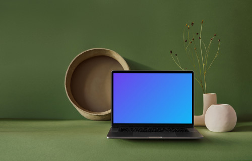 MacBook mockup on a green slab with flower vase at the side
