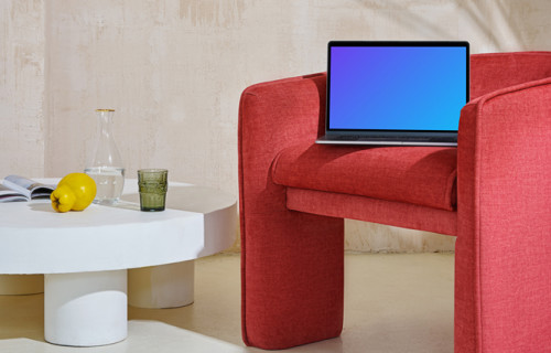 MacBook mockup on a red couch with a center table close by