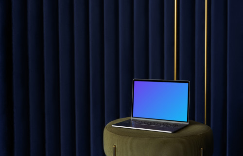 MacBook mockup on a sofa stool with a blue curtain in the background