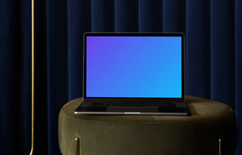 MacBook mockup on a sofa stool with blue curtain in the background