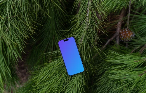 A smartphone mockup laying on top of a pine tree