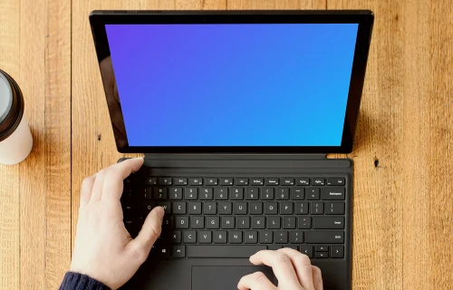 Black Microsoft Surface Laptop mockup on a wooden table.