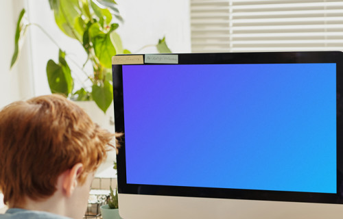 Child writing in front of an iMac mockup