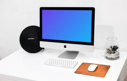 iMac mockup em uma mesa de trabalho organizada ao lado de um vaso de água