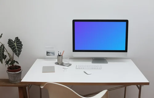 iMac mockup sobre una mesa blanca con una maceta al lado