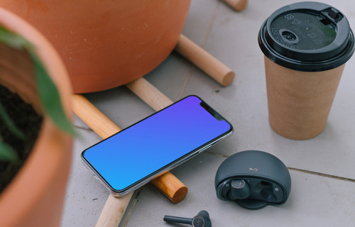  iPhone 12 mockup à côté d'une tasse de café et d'écouteurs