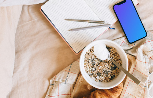 iPhone 12 Pro mockup on a bed, with a tray of food at its side