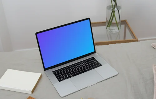 MacBook mockup on a bed with a jug and ceramic on a wooden tray and a notebook at the side