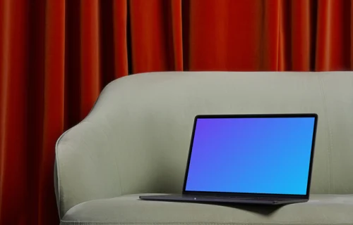 MacBook mockup on a couch with a red curtain in the background