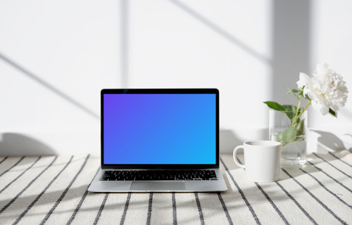 MacBook mockup sur un tapis à motifs avec une tasse sur le côté