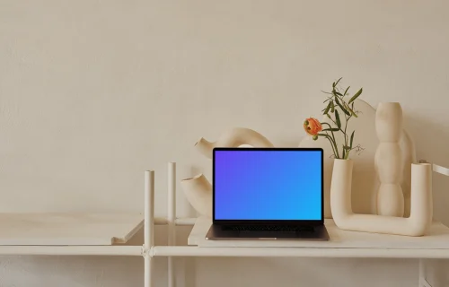 MacBook mockup em uma mesa com um vaso de flores cor de pêssego ao lado