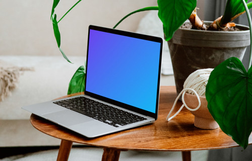 MacBook mockup on a wooden table with flower pot