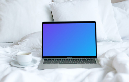 MacBook mockup placed on a white bed with a cup of coffee at the side