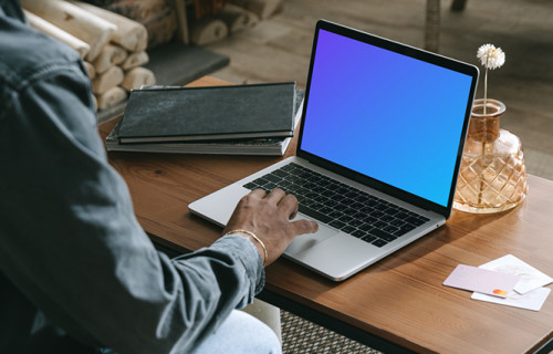 MacBook user shopping with a MacBook on the table and a debit card beside it mockup.