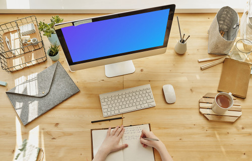 Mockup of a child writing in a book with an iMac on the table