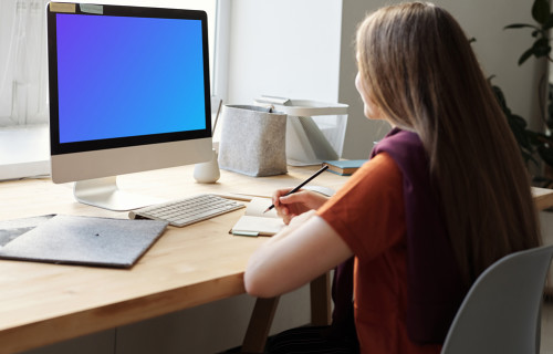 Mockup of a young girl using her iMac on a table