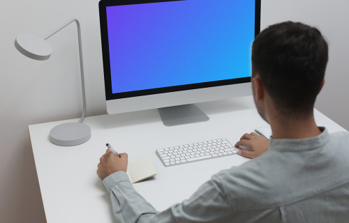 Mockup of man using iMac on a white table in a home office setting