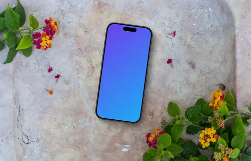 Smartphone mockup on a stone surface with flowers