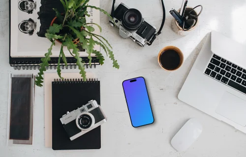 Top view of phone mockup with a MacBook Pro and camera on the side