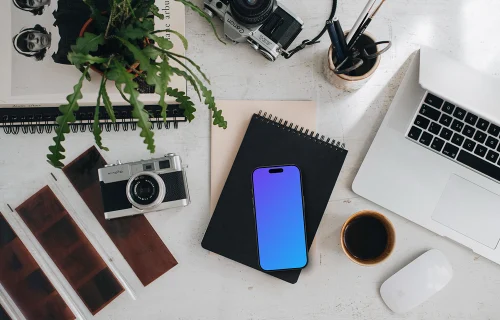 Top view of phone mockup with analog cameras and book