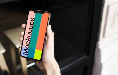 Holding iPhone X mockup in front of the shop
