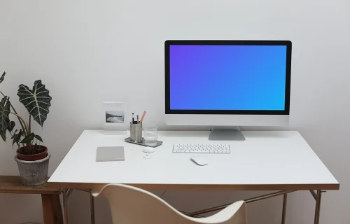 iMac mockup on a white table with a flower pot by the side