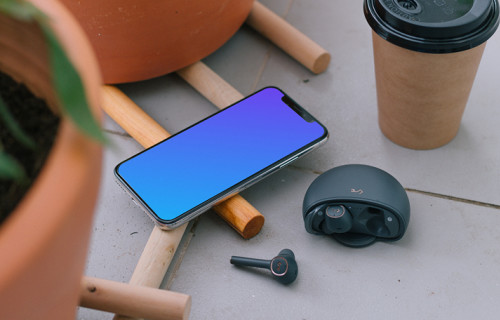 iPhone 12 mockup beside to a cup of coffee and earbuds